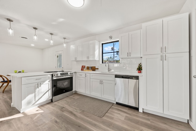 kitchen with light hardwood / wood-style flooring, kitchen peninsula, decorative light fixtures, white cabinets, and appliances with stainless steel finishes