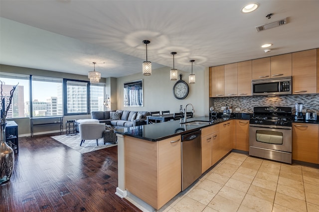 kitchen featuring sink, light hardwood / wood-style flooring, kitchen peninsula, decorative light fixtures, and appliances with stainless steel finishes