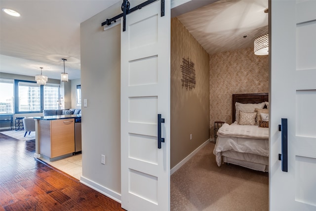 bedroom featuring a barn door and light hardwood / wood-style flooring