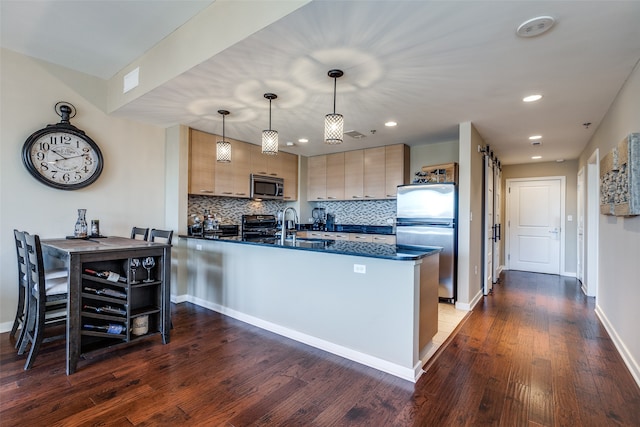 kitchen with pendant lighting, dark hardwood / wood-style floors, light brown cabinetry, appliances with stainless steel finishes, and kitchen peninsula