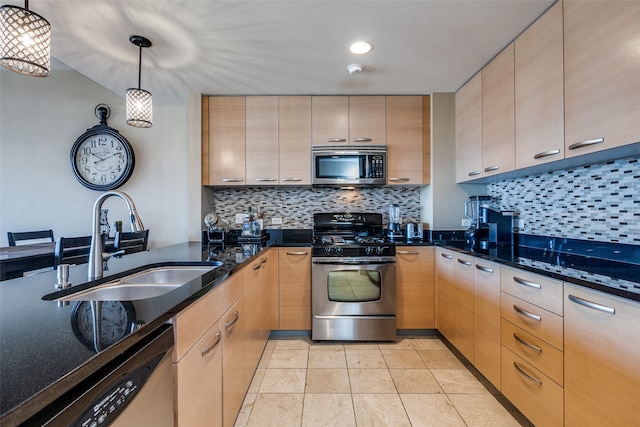 kitchen with light brown cabinetry, hanging light fixtures, dark stone countertops, and stainless steel appliances