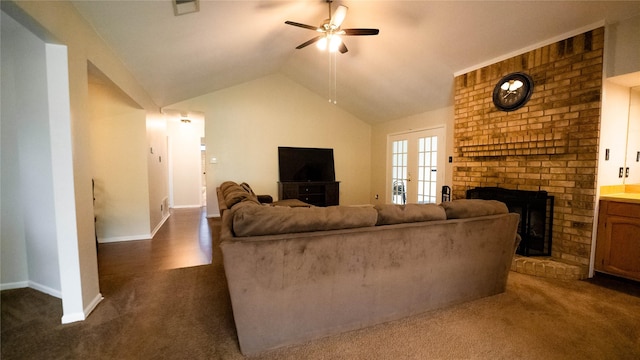 living room featuring ceiling fan, vaulted ceiling, a brick fireplace, and dark carpet