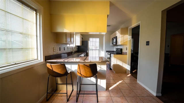 kitchen featuring electric range oven, a kitchen breakfast bar, sink, kitchen peninsula, and light tile patterned flooring