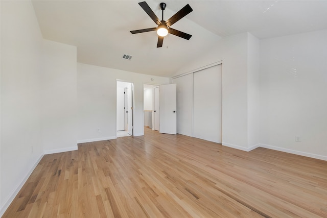 unfurnished bedroom with a closet, ceiling fan, light hardwood / wood-style flooring, and lofted ceiling