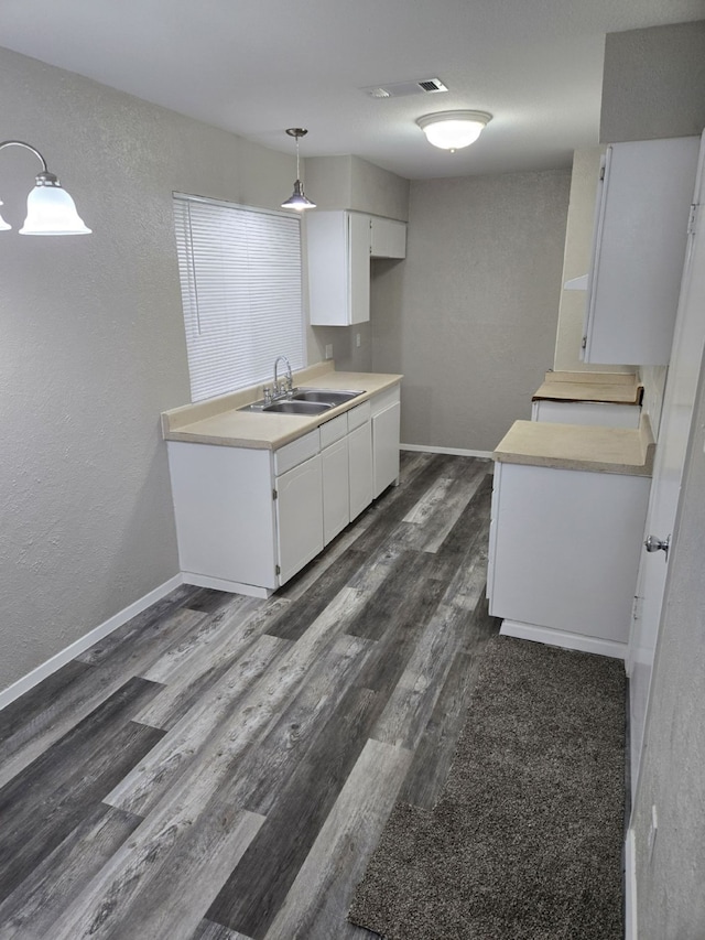 kitchen featuring white cabinets, decorative light fixtures, dark hardwood / wood-style floors, and sink