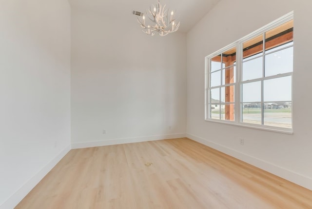 unfurnished room with a notable chandelier, wood finished floors, visible vents, and baseboards