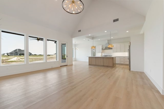 unfurnished living room with a chandelier, recessed lighting, light wood-type flooring, and baseboards