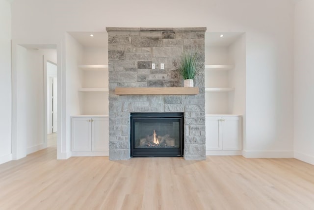 room details with baseboards, a fireplace, built in features, and wood finished floors