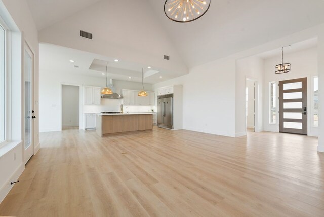 unfurnished living room featuring light wood-style flooring, a chandelier, and a wealth of natural light