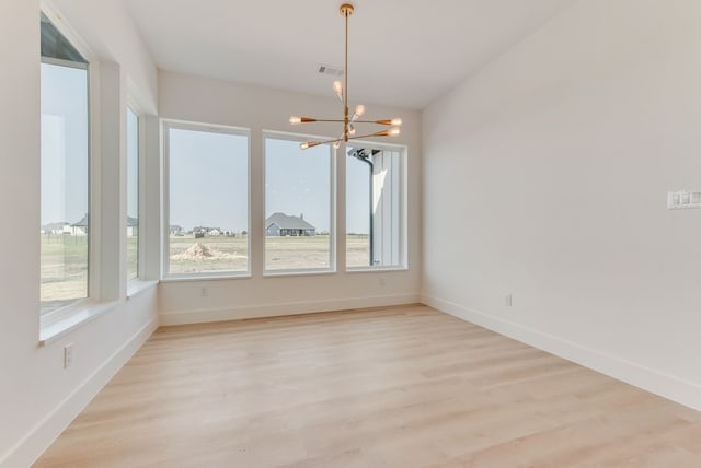 unfurnished dining area with light wood-style floors, baseboards, visible vents, and a chandelier