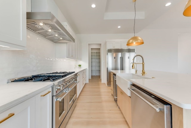 kitchen with a kitchen island with sink, stainless steel appliances, premium range hood, white cabinets, and backsplash