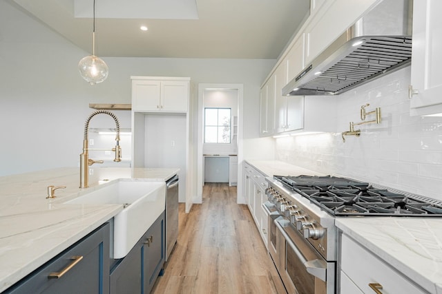 kitchen with white cabinetry, wall chimney exhaust hood, hanging light fixtures, and light stone counters