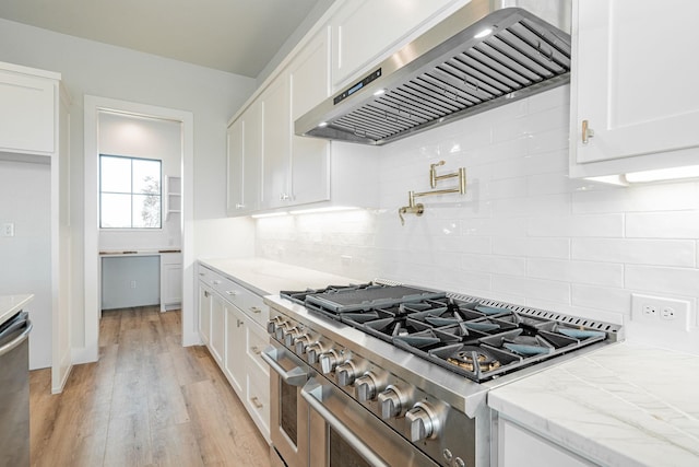 kitchen featuring white cabinetry, stainless steel appliances, light hardwood / wood-style floors, and exhaust hood