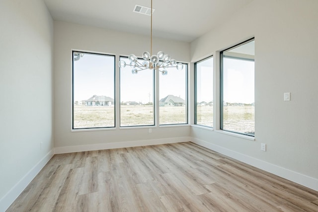 unfurnished dining area with an inviting chandelier and light hardwood / wood-style floors