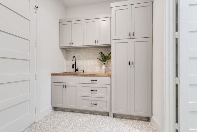 bar with a sink, baseboards, and backsplash