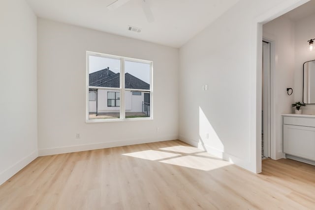 spare room with baseboards, wood finished floors, visible vents, and a ceiling fan