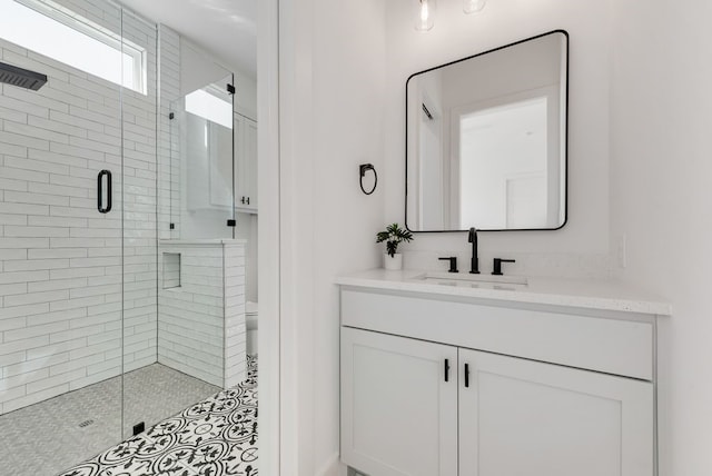 bathroom with toilet, a shower stall, and vanity