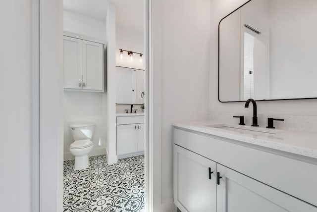 bathroom featuring toilet, two vanities, a sink, and tile patterned floors