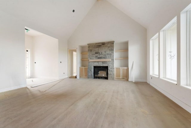 unfurnished living room featuring built in shelves, a stone fireplace, high vaulted ceiling, and light wood-type flooring