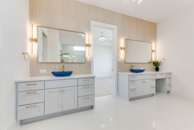 full bathroom with two vanities, a sink, and baseboards