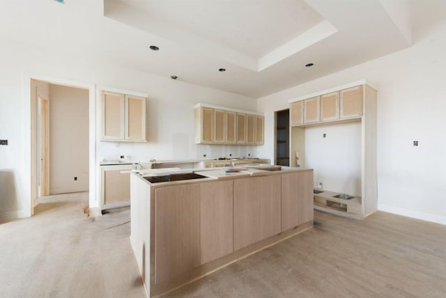 kitchen featuring a center island, a tray ceiling, light brown cabinets, black electric cooktop, and light hardwood / wood-style flooring