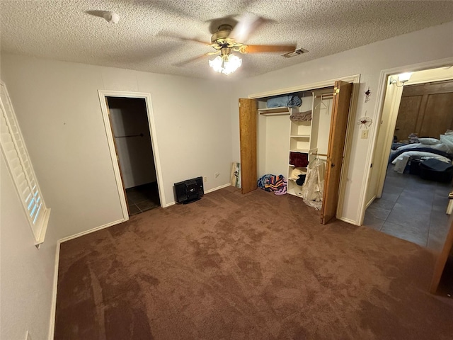 unfurnished bedroom with dark colored carpet, ceiling fan, and a textured ceiling