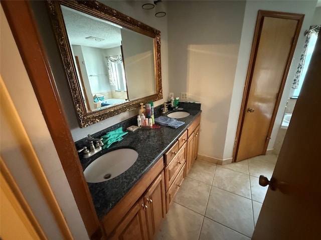 full bath with a textured ceiling, tile patterned floors, double vanity, and a sink