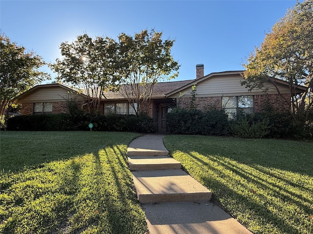 view of front facade featuring a front lawn, brick siding, and a chimney