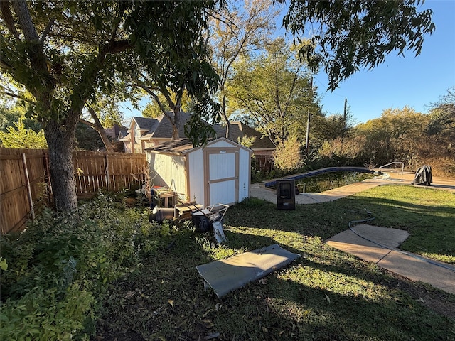 view of yard featuring a fenced backyard, a fenced in pool, an outdoor structure, and a shed