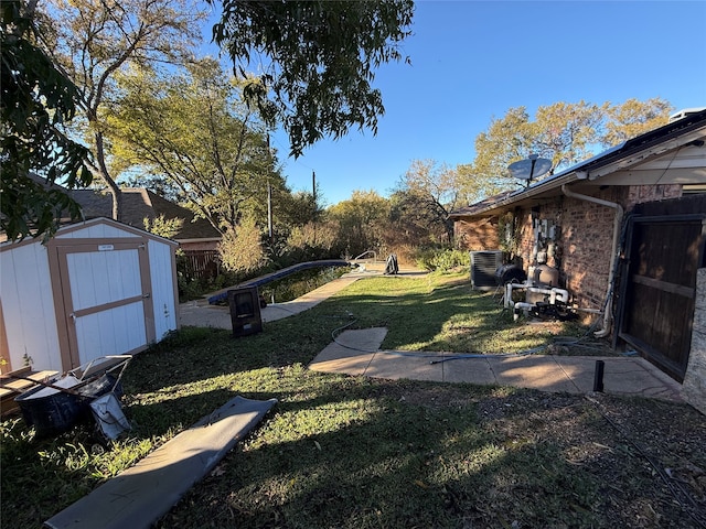 view of yard featuring central air condition unit, fence, an outbuilding, and a shed