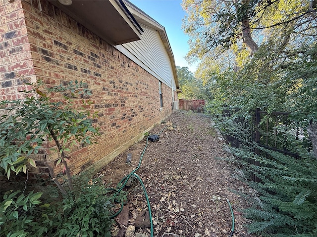 view of side of property with brick siding and fence