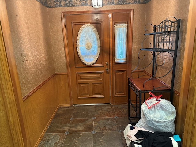 doorway with a wainscoted wall, wood walls, and stone finish flooring