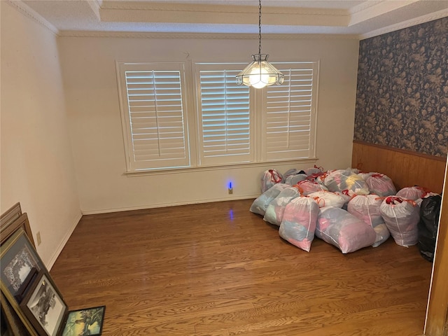 bedroom featuring a wainscoted wall, a raised ceiling, crown molding, and wood finished floors