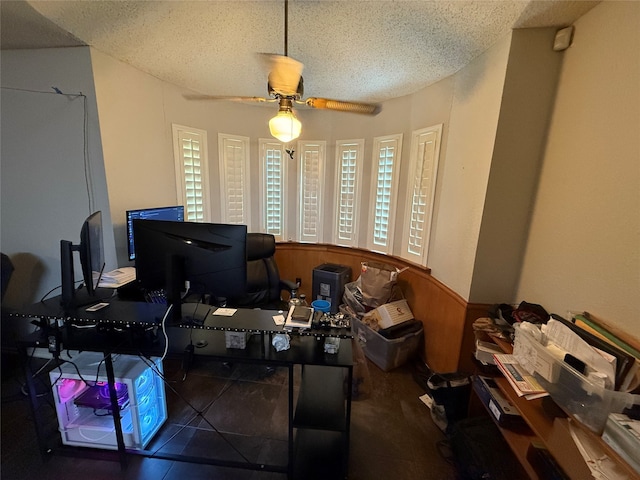 tiled home office with ceiling fan, wooden walls, and a textured ceiling