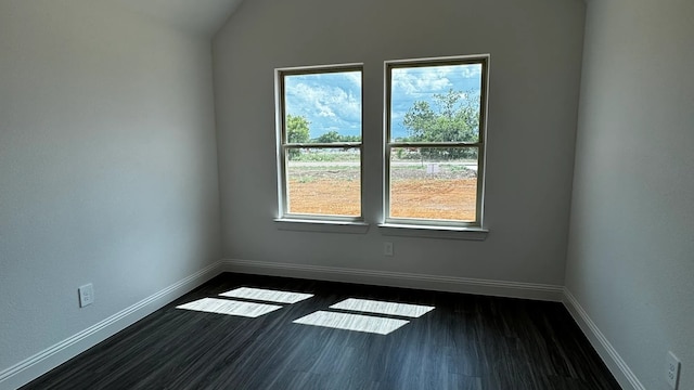 spare room featuring vaulted ceiling and dark hardwood / wood-style floors