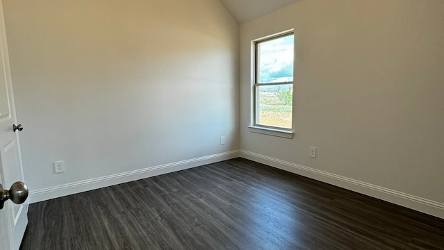 spare room featuring lofted ceiling and dark hardwood / wood-style floors