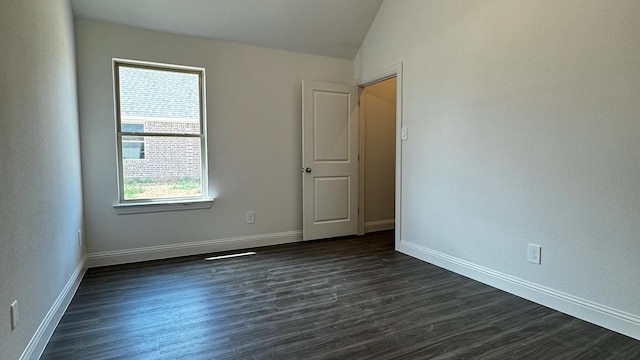 empty room with dark wood-type flooring, a healthy amount of sunlight, and vaulted ceiling