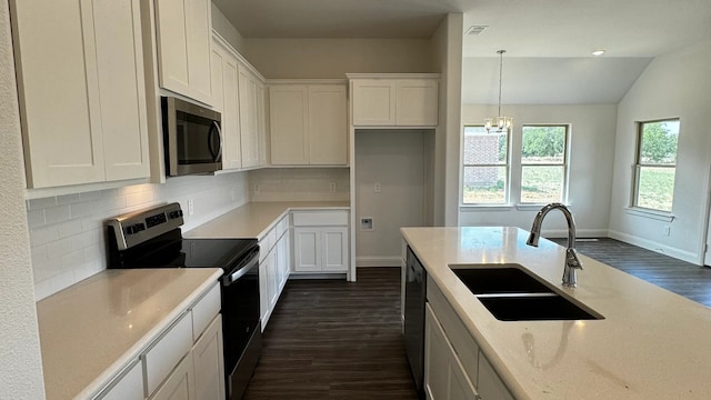 kitchen with dark wood-type flooring, sink, hanging light fixtures, vaulted ceiling, and stainless steel appliances