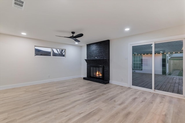 unfurnished living room with ceiling fan, light wood-type flooring, and a fireplace