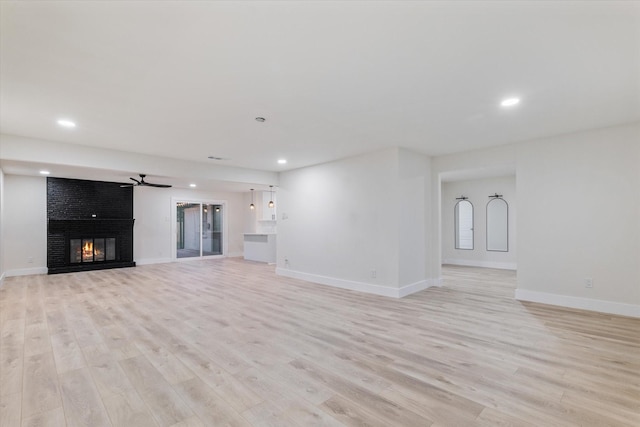 unfurnished living room featuring ceiling fan, light hardwood / wood-style flooring, and a brick fireplace