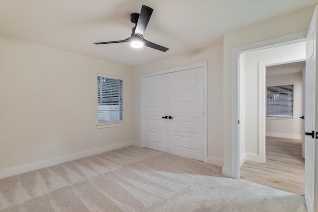 unfurnished bedroom featuring ceiling fan, a closet, and light colored carpet