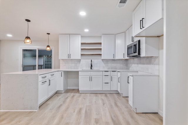 kitchen with white cabinetry, sink, tasteful backsplash, pendant lighting, and light hardwood / wood-style floors