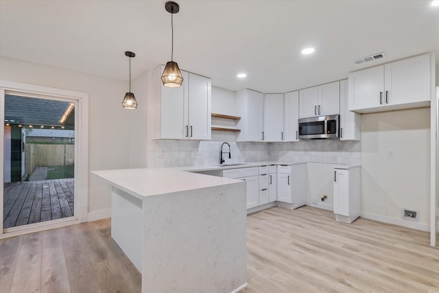 kitchen featuring white cabinets, light hardwood / wood-style floors, and hanging light fixtures