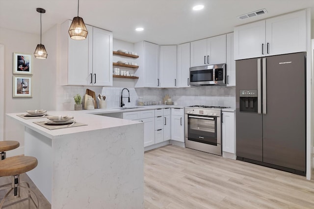 kitchen with appliances with stainless steel finishes, backsplash, white cabinetry, and a breakfast bar area