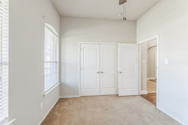 unfurnished bedroom with multiple windows, light carpet, and a closet