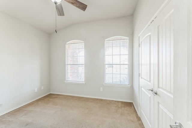 spare room with light carpet, vaulted ceiling, and ceiling fan