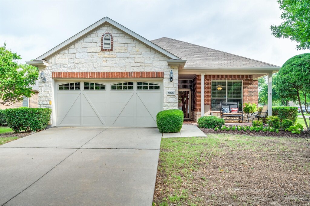 906 Pasatiempo Dr, Frisco, TX 75036 - view of front of house with an attached garage, stone siding, a front lawn, and driveway