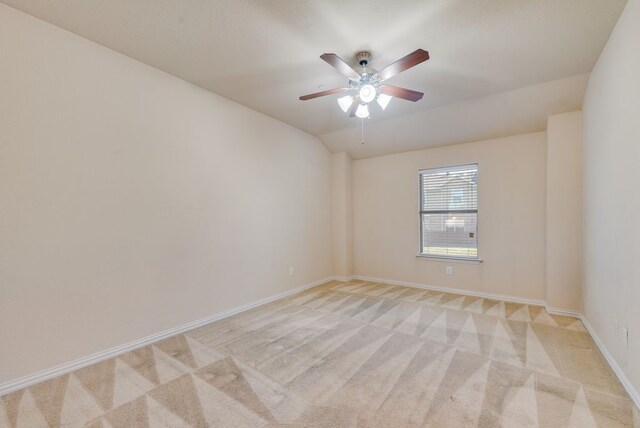 unfurnished room featuring baseboards, ceiling fan, lofted ceiling, and light colored carpet