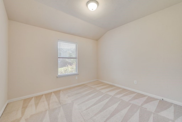 spare room with a textured ceiling, lofted ceiling, and light carpet