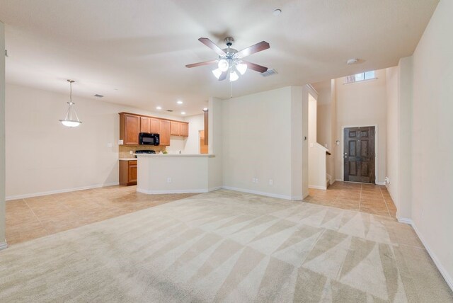 kitchen featuring brown cabinetry, visible vents, a sink, black appliances, and a peninsula